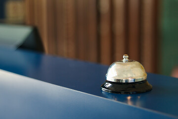 Closeup of vintage silver bell on a wood stand at hotel reception service desk.