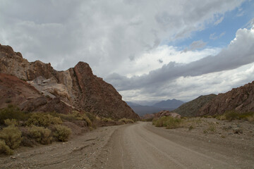 Road trip into the wild. Traveling along the empty dirt road across the arid desert and rocky mountains.