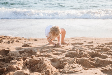 View of playful toddler girl playing on sand beach