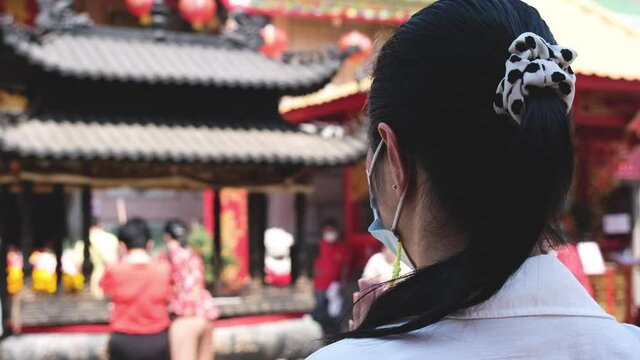 Asian woman from behind is making a wish at a Chinese temple.