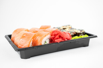 take away sushi in plastic containers, philadelphia rolls and unagi maki, soy sauce, pink ginger, wasabi, sushi delivery concept