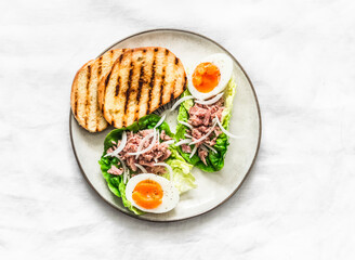 Roman salad  with canned tuna and boiled egg - delicious breakfast, tapas, snack on a light background, top view