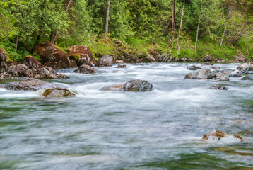 Naklejka na ściany i meble Majestic mountain river in slow motion with rocky background in Vancouver, Canada.