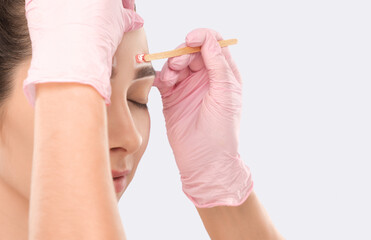 Makeup artist does facial hair removal procedure. Beautiful girl with blue eyes having Permanent...