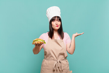 young chef woman feeling puzzled and confused, doubting, weighting or choosing different options with funny expression