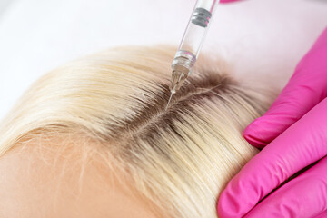 Cosmetologist does injections therapy against hair loss and anti-dandruff of a beautiful woman in a...