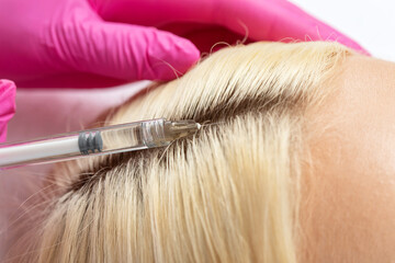 Cosmetologist does injections therapy against hair loss and anti-dandruff of a beautiful woman in a...