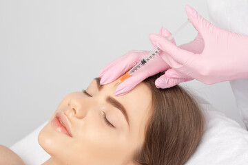 Fototapeta premium Cosmetologist makes rejuvenating anti wrinkle injections on the face of a beautiful woman. Female aesthetic cosmetology in a beauty salon.