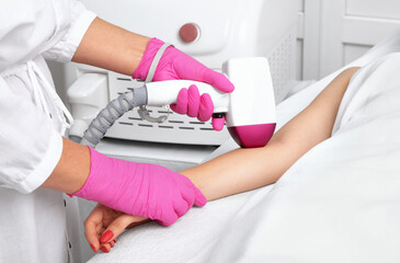 Obraz na płótnie Canvas Elos epilation hair removal procedure on a womans body. Beautician doing laser rejuvenation on the hand in a beauty salon. Facial skin care. Hardware ipl cosmetology