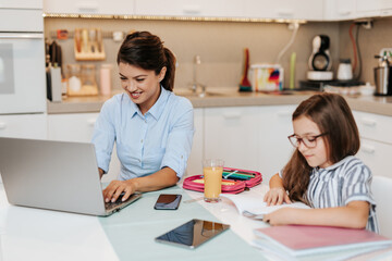 Mother works from home due to coronavirus while her daughter does her homework.
