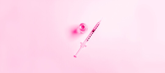 Syringe and vaccine or medicine vial on pink background with copy space for immunization against COVID-19, beauty injections