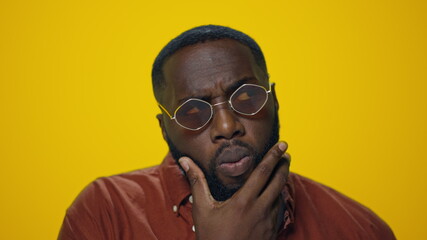 Portrait of thoughtful african american man thinking on yellow background.