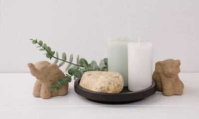 Modern stylish element composition with stone podium, Eucalyptus,elephant statue and candle spa on black tray in white room interior