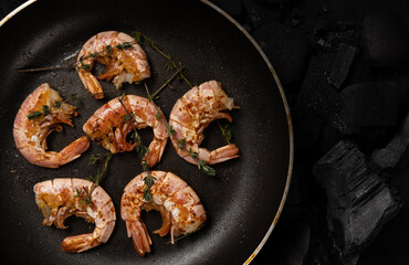 Prawns fried with herbs Thyme in a frying pan on a dark background. Seafood appetizer, no people, horizontal orientation, top view