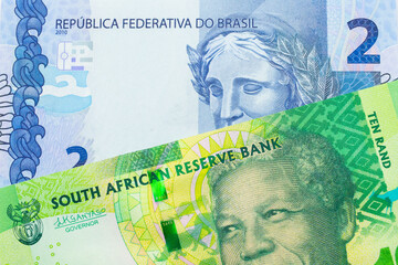 A macro image of a shiny, green 10 rand bill from South Africa paired up with a blue two real bank note from Brazil.  Shot close up in macro.