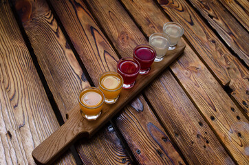 A set of colorful alcoholic tinctures on berries and fruits on a wooden background