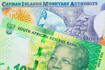 A macro image of a shiny, green 10 rand bill from South Africa paired up with a colorful one dollar note from the Cayman Islands.  Shot close up in macro.