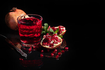 Pomegranate juice in a glass and pomegranate slices on a dark background. Vitamin drink. Still life.
