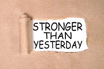 stronger than yesterday. text on white paper over torn paper background.