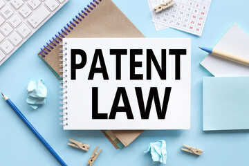 Patent Law. text on white notepad paper on blue background. near the blue sticks and a white...