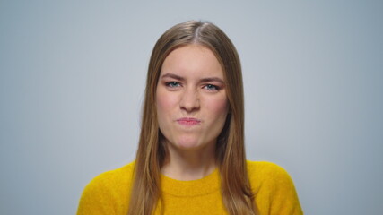 Portrait of stressed woman posing with hands gestures on grey background.