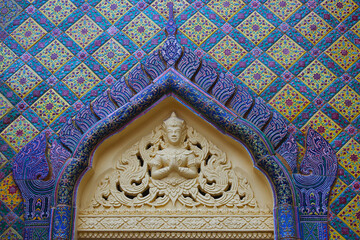 Angel statue and Thai pattern above the gate of a Thai temple