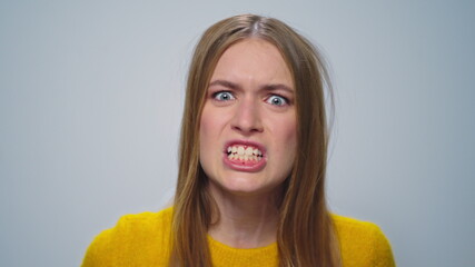 Portrait of angry woman screaming with aggressive emotion at camera in studio.