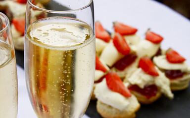 Glass of champagne with scones jam and cream, topped with strawberries
