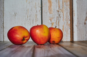 Apples lit from the sun decoratively lying on a wooden underground.