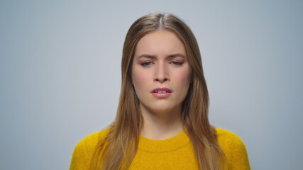 Portrait of beautiful ill girl sneezing at camera on grey background. 