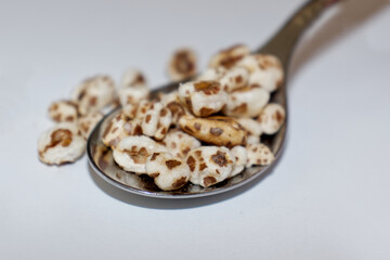 A tablespoon with puffed wheat on a white background 