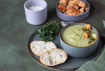 Vegetarian cream soup of green vegetables served with mint and seeds on concrete background. Clean eating, healthy food concept.