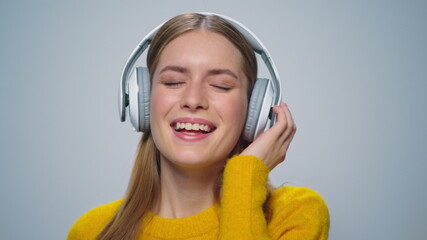 Closeup smiling woman listening music in headphones on grey background. 
