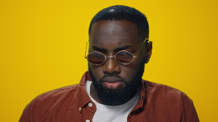 Portrait of smiling african american man dancing on yellow background.