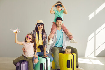 Happy laughing family with children sitting on suitcases luggage bag isolated portrait on studio...