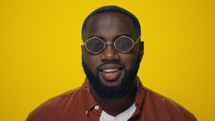 Portrait of african american man smiling at camera on yellow background.