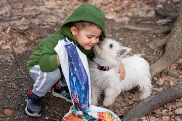 Little boy playing with his pet. Boy play with puppy. Children and dog in garden.