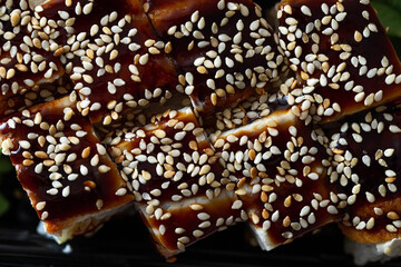 Freshly prepared rice and eel rolls with sweet sesame sauce in a plastic square plate. Chinese food from the delivery service