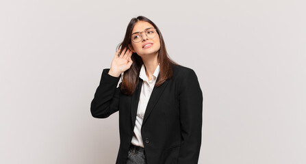young business woman looking serious and curious, listening, trying to hear a secret conversation...
