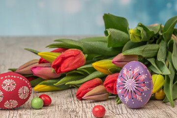 Painted Eggs In Basket With Tulips On Natural Wooden Plank