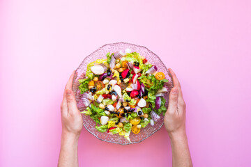 hands of a woman holding a mediterranean salad