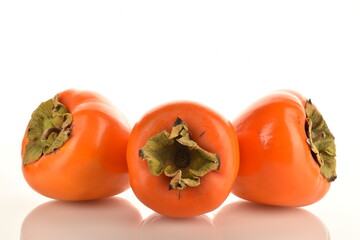 Three juicy organic persimmons, close-up, isolated on white.