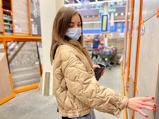 Fototapeta premium girl wearing a protective mask against coronavirus in a store