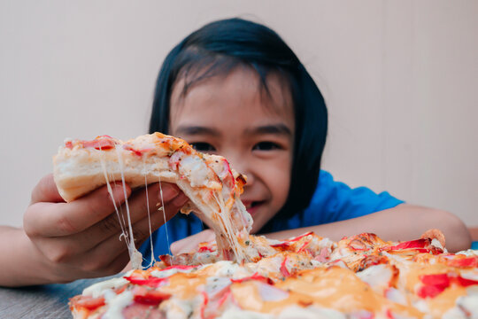 Pizza and kids concept, slices pizza portion on hand to eating, fast food snack for tasty and delicous on table, many cheese in surface for order delivery, happy time for hungry children in family