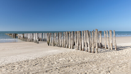 Rows of breakwaters or groynes on sandy beach disappearing in the North Sea in Zeeland, the Netherlands