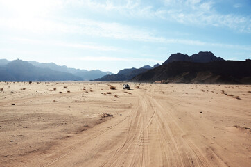 Jordan, Wadi Rum Desert: Scenic landscape view of the desert with mountains and tire tracks on the sand 