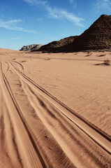 Jordan, Wadi Rum Desert: Scenic landscape view of the desert with mountains and tire tracks on the sand 