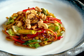 Sweet and sour noodles with peanuts, vegetables and onions, served in a white bowl. Wok noodles. Isolated over black background. Street thai food