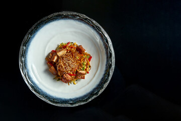 Sweet and sour glass noodles with pork, vegetables and onions, served in a white bowl. Wok noodles. Isolated over black background. Street thai food