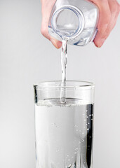 Pouring water from a bottle on glass on a light background. Natural mineral water .